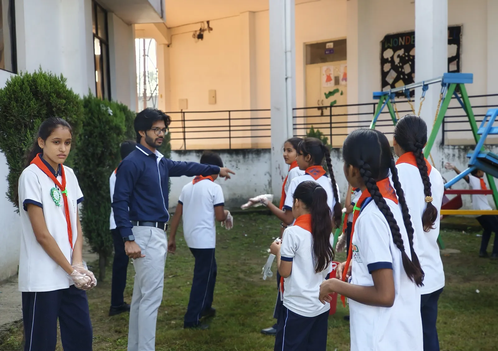 Scouts and guides in orange scarves with a teacher in the play area