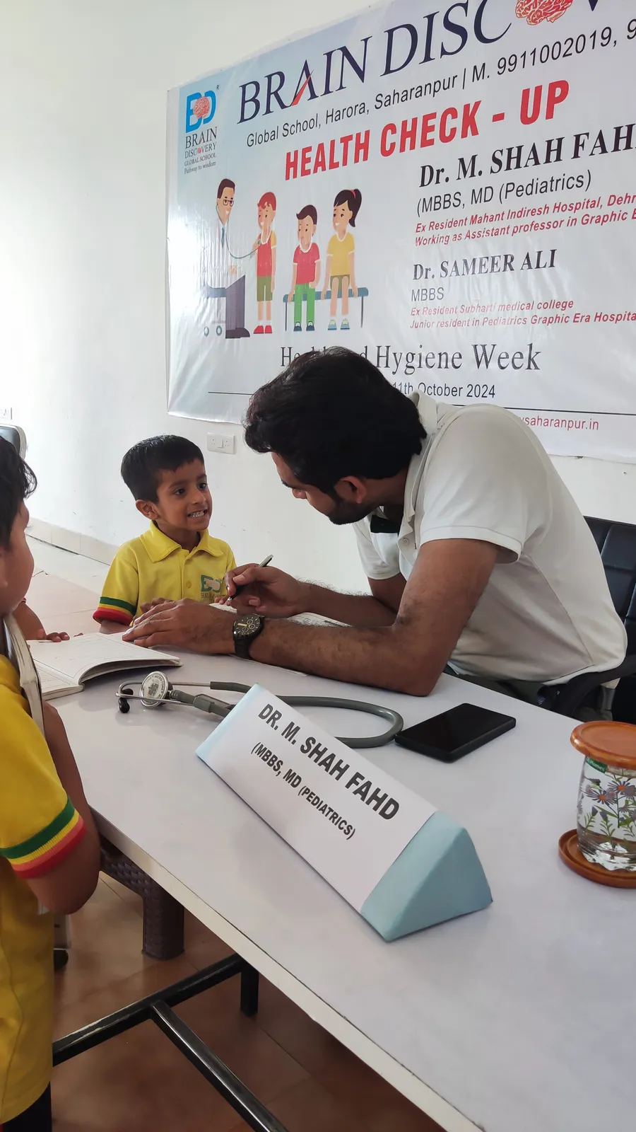 A boy smiles up at the doctor writing up his check-up