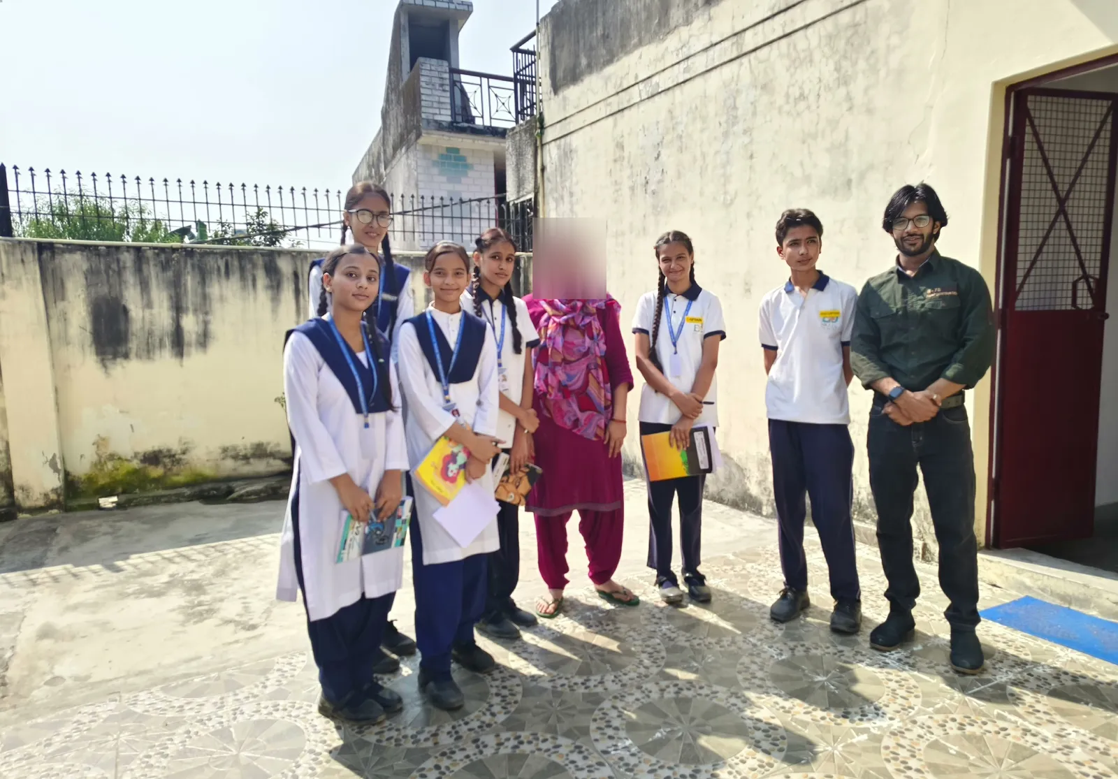 Another house team and a teacher with a resident in a sunny courtyard