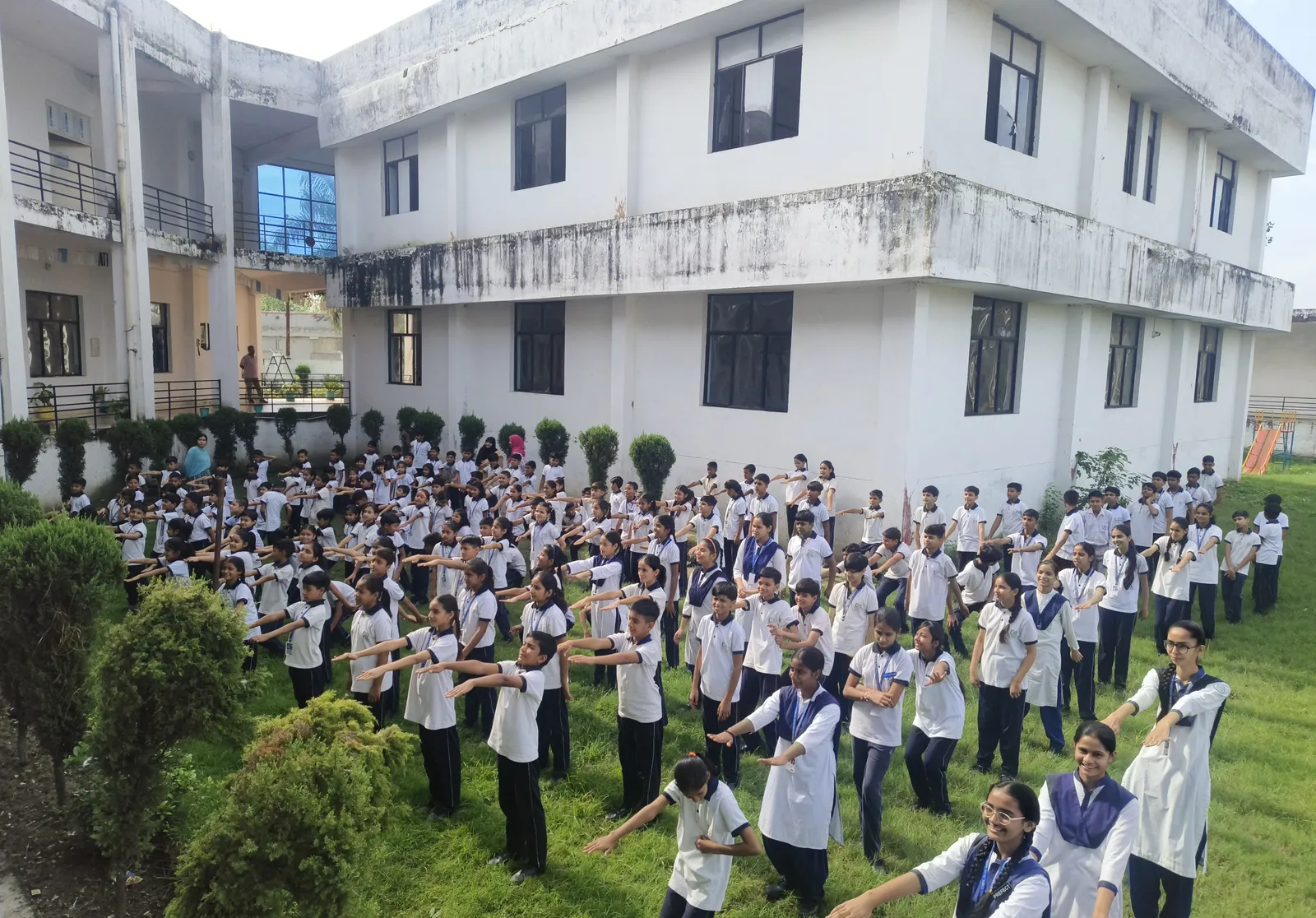 Rows of senior students on the lawn stretching their arms out in front of them