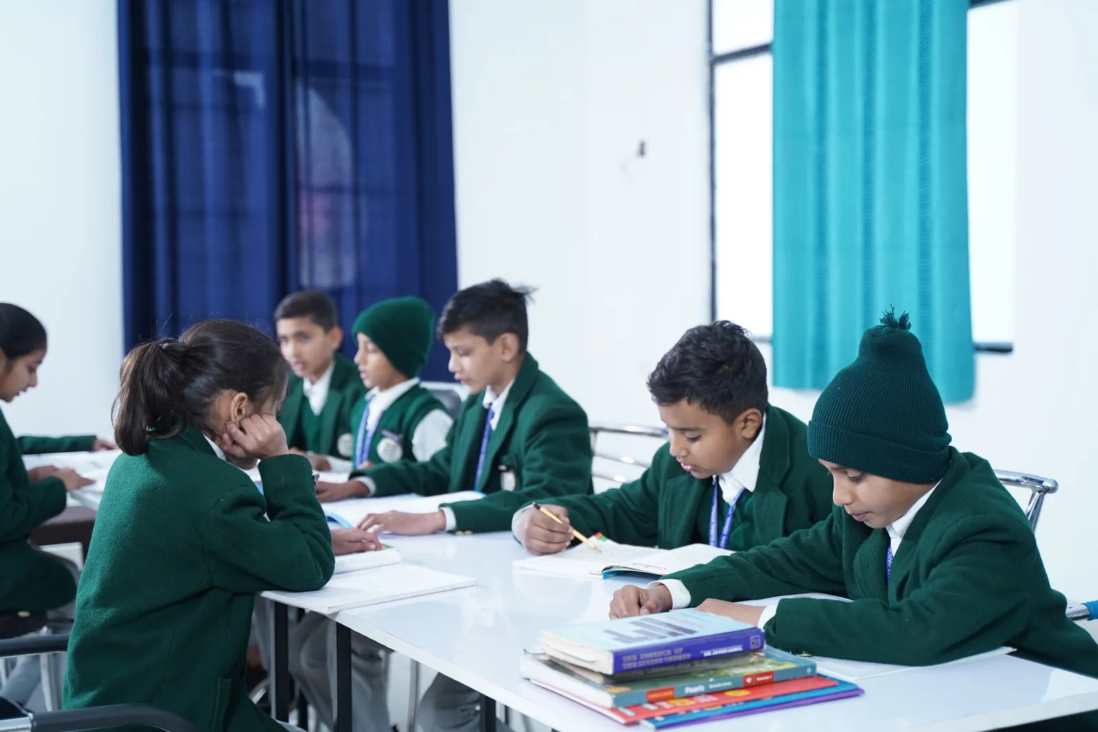Students in green blazers working together at a classroom table